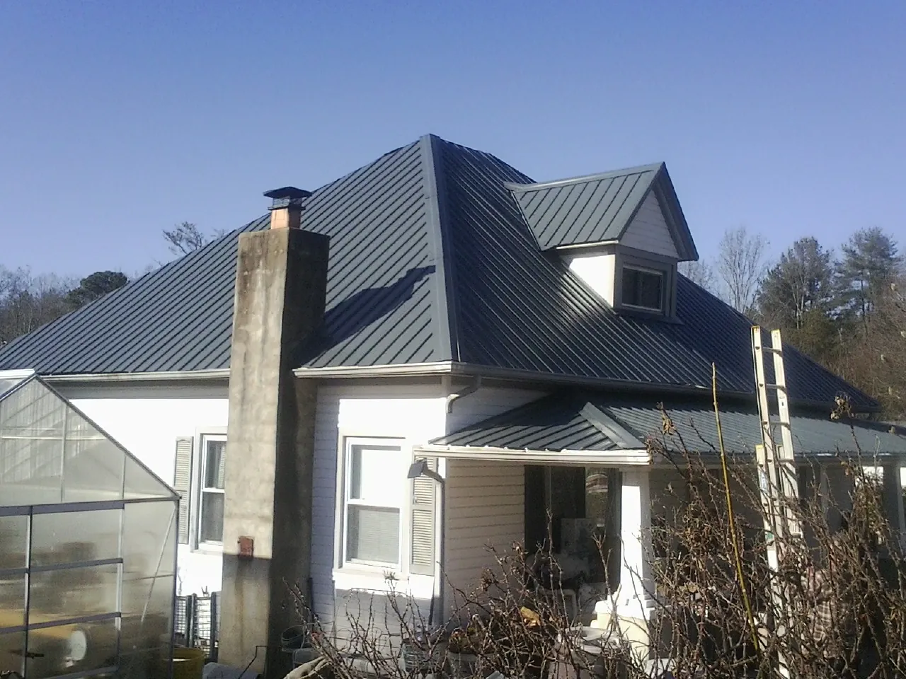 Dark blue standing seam metal roof on a white farmhouse with dormer — Slate & Tile Roof Repair by Roofing Brothers in Boyers