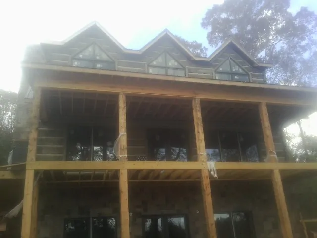 Dormers and porch framing on a large log home under construction — Roof Coating work by our crew in Boyers