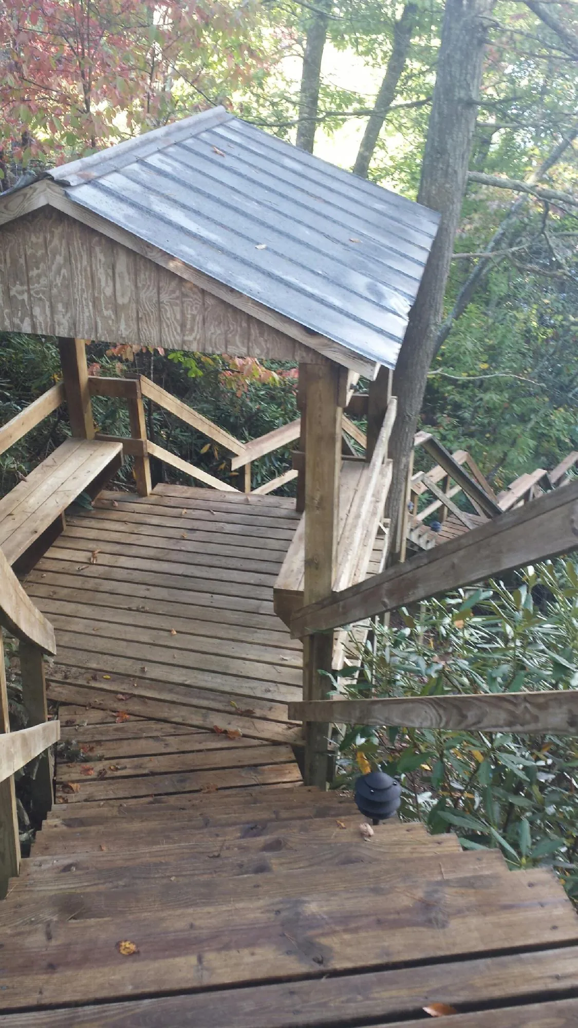 Metal roofed shelter over wooden steps on a wooded walkway — Skylight Repair & Installation work by our crew in Boyers