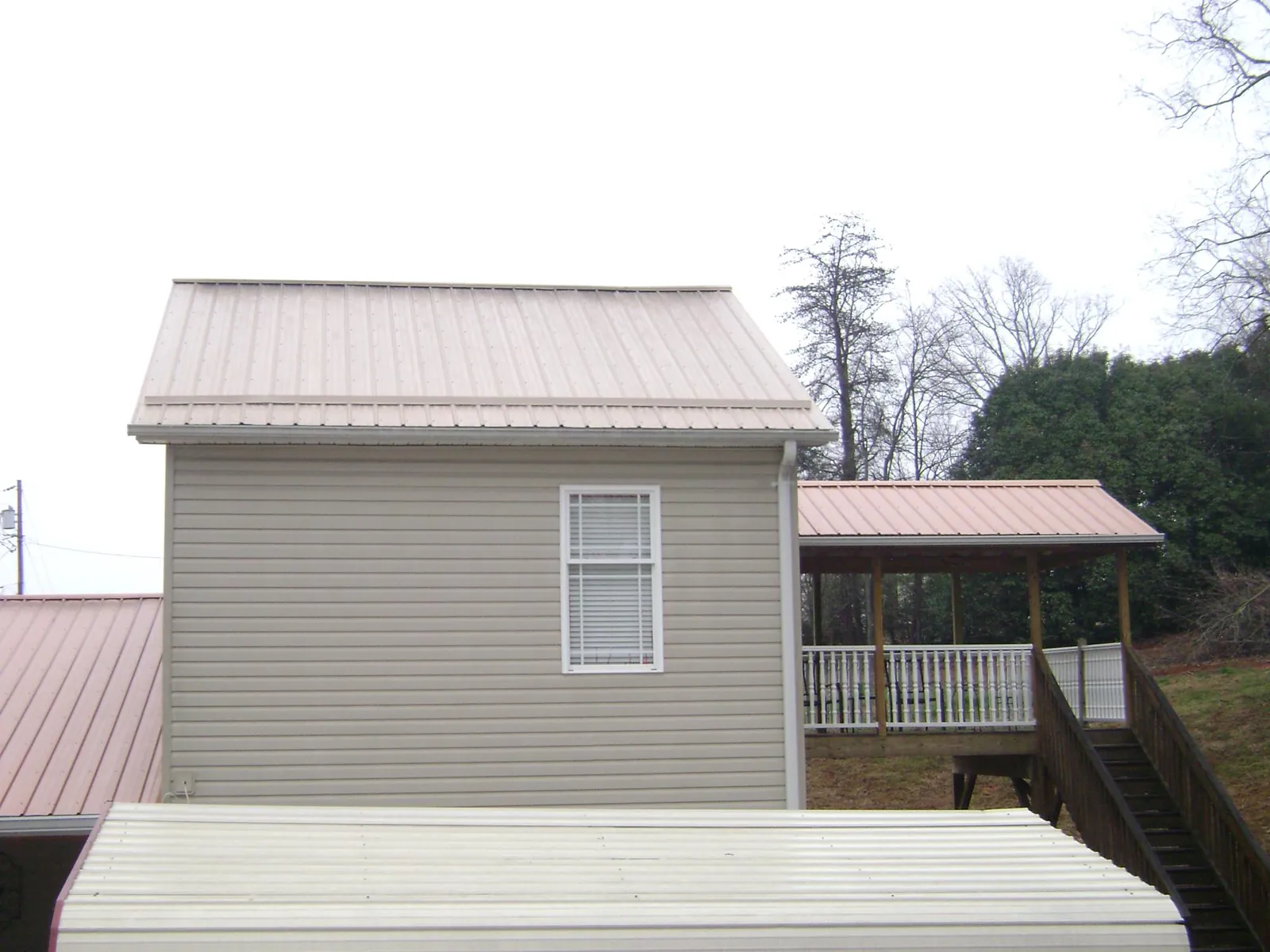 Tan metal roofs on a two story addition and attached porch, from a Roof Replacement job in Boyers