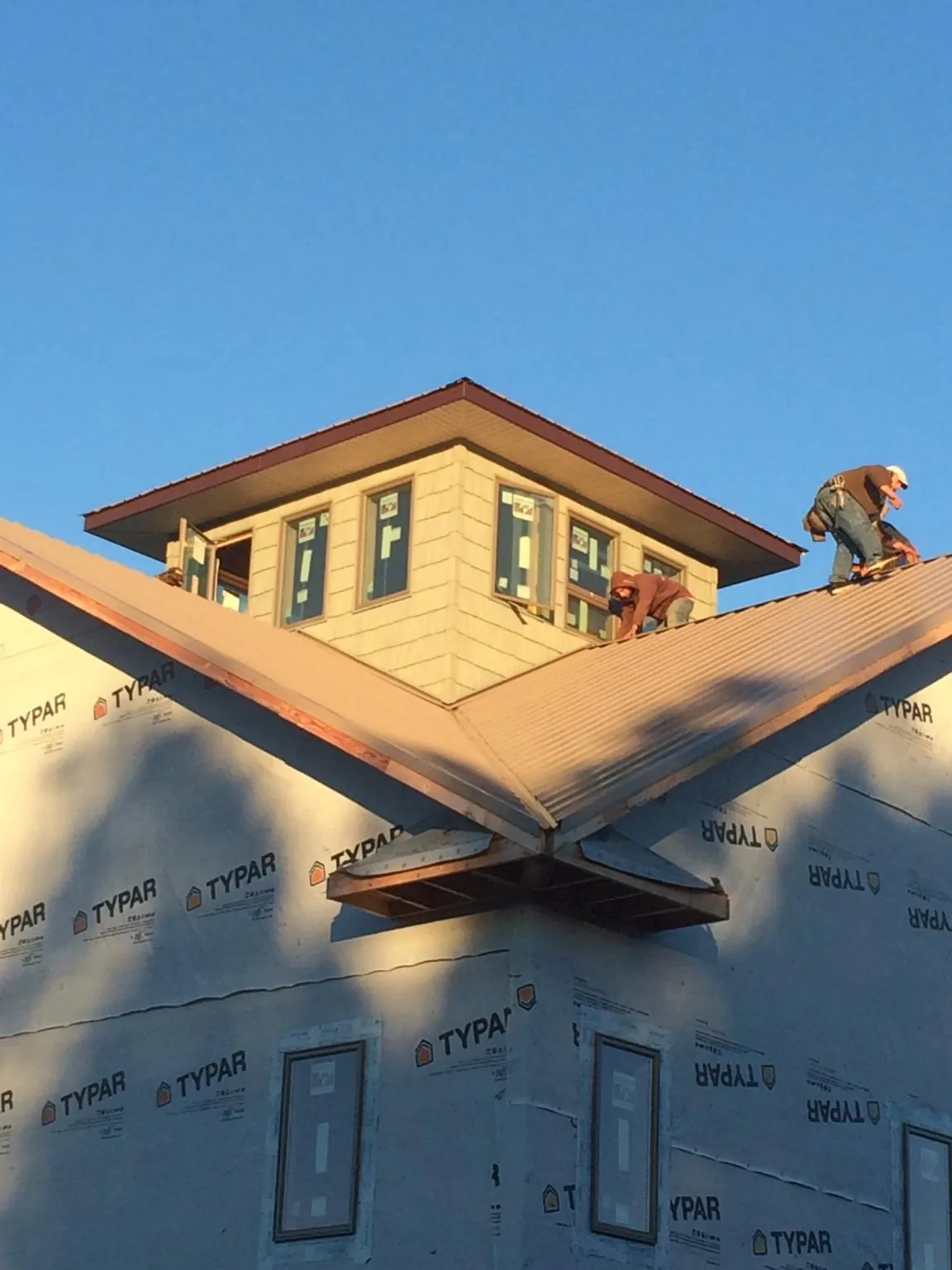Roofers working around a rooftop cupola on a new metal roof at sunset — Roof Waterproofing in Boyers by Roofing Brothers